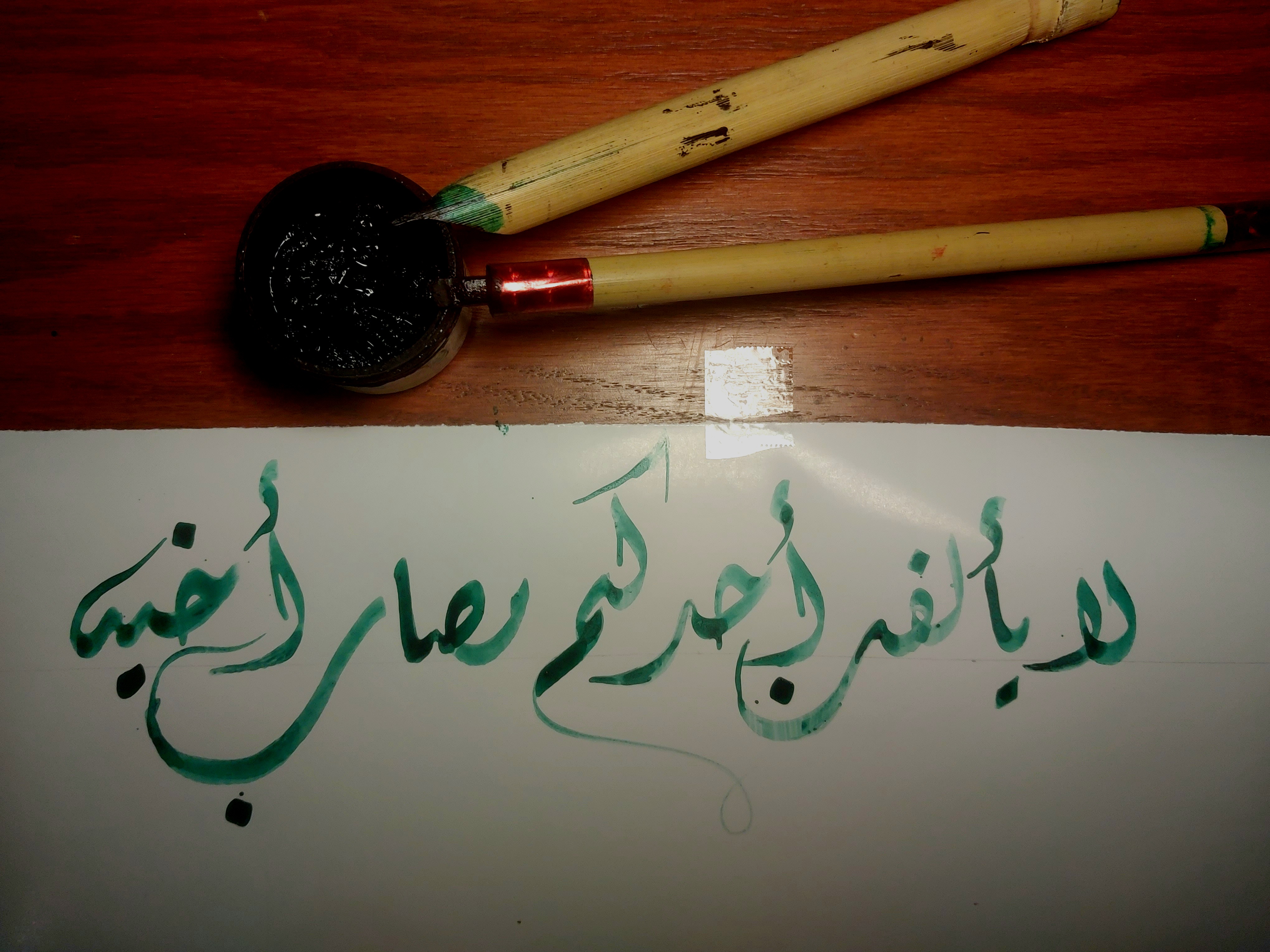 Hadith in green ink beside the reed pens used to write it: Lā yaʾlafanna aḥadukum maṣāb akhīh